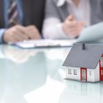 Businessman signs contract behind home architectural model